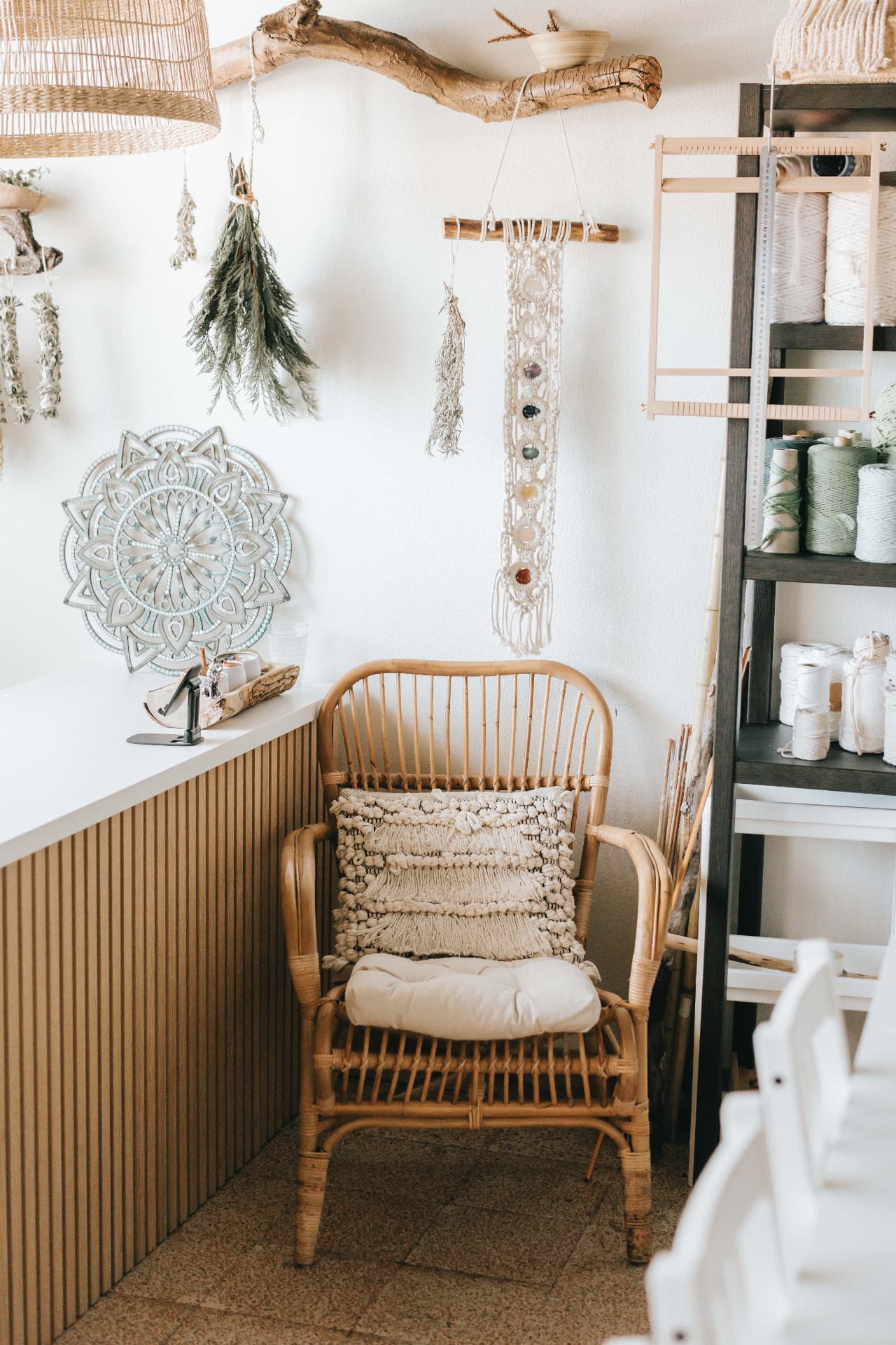Estante com novelos e fios de macramé, tear e materiais no atelier TEULU